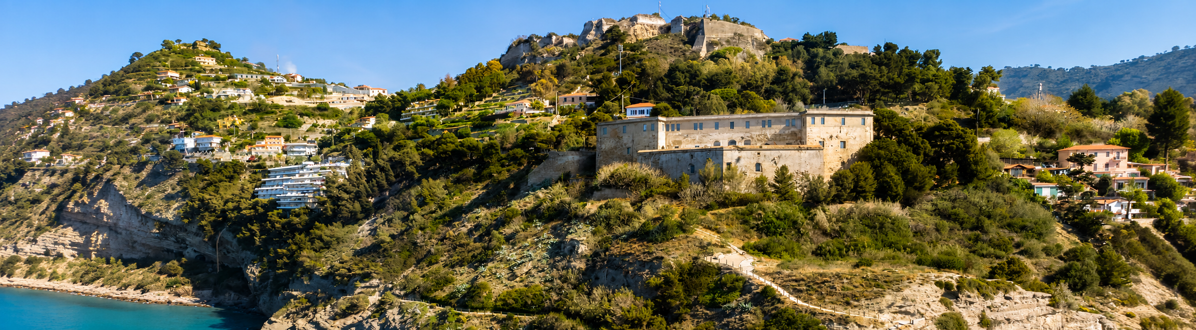 Veduta panoramica di una fortezza su una collina affacciata sul mare.